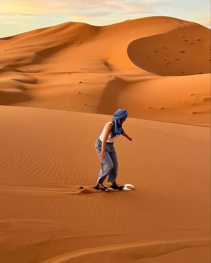 Merzouga City Traveller with a desert scarf walking on Sahara dunes