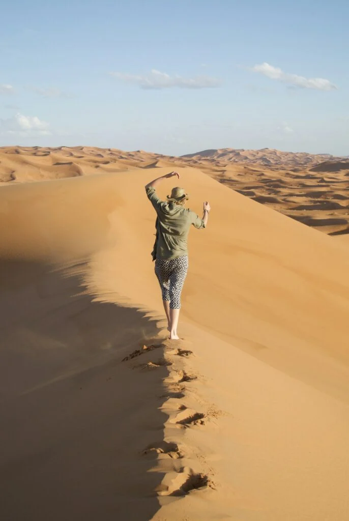 What to Pack for a Morocco Desert Trip 1 Man walking across a sand dune in the Erg Chebbi